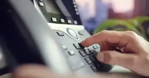 Person tippt Nummer in Bürotelefon ein